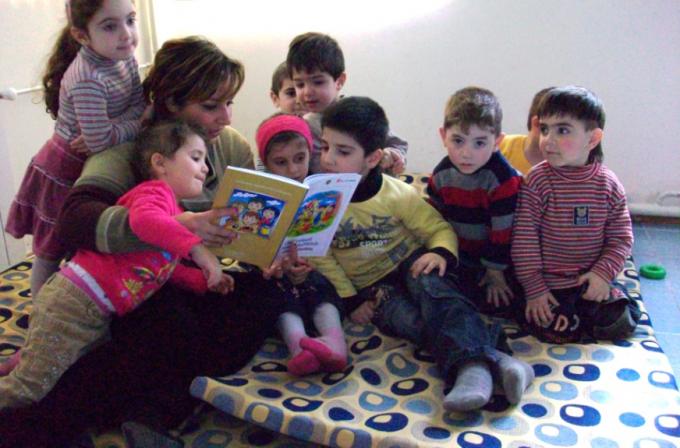 Teacher reading a book for children at a preschool established for refugee and former refugee children